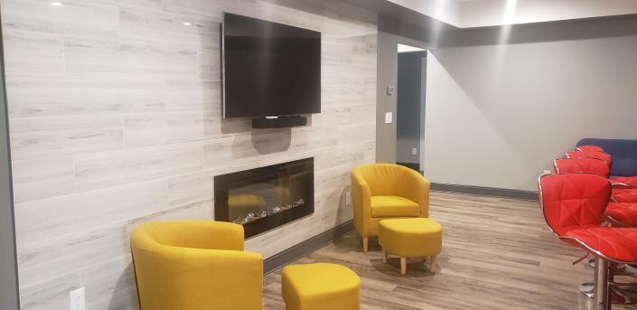 Modern basement living area with fireplace and TV