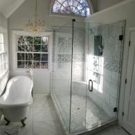 Large shower with intricate tile and claw foot tub