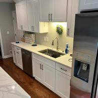 Remodeled kitchen with white cabinets and wood flooring