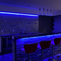 Wet bar in basement with feature lighting