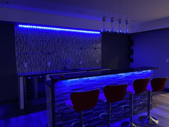 Wet bar in basement with feature lighting