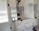 Glass shower and intricate tile on shower walls and bathtub