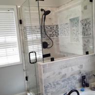 Glass shower and intricate tile on shower walls and bathtub